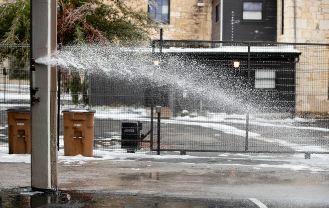 A broken pipe spews water outside the offices of the Texas Association of Community Colleges on Rio Grande Street in Austin on Feb. 18.