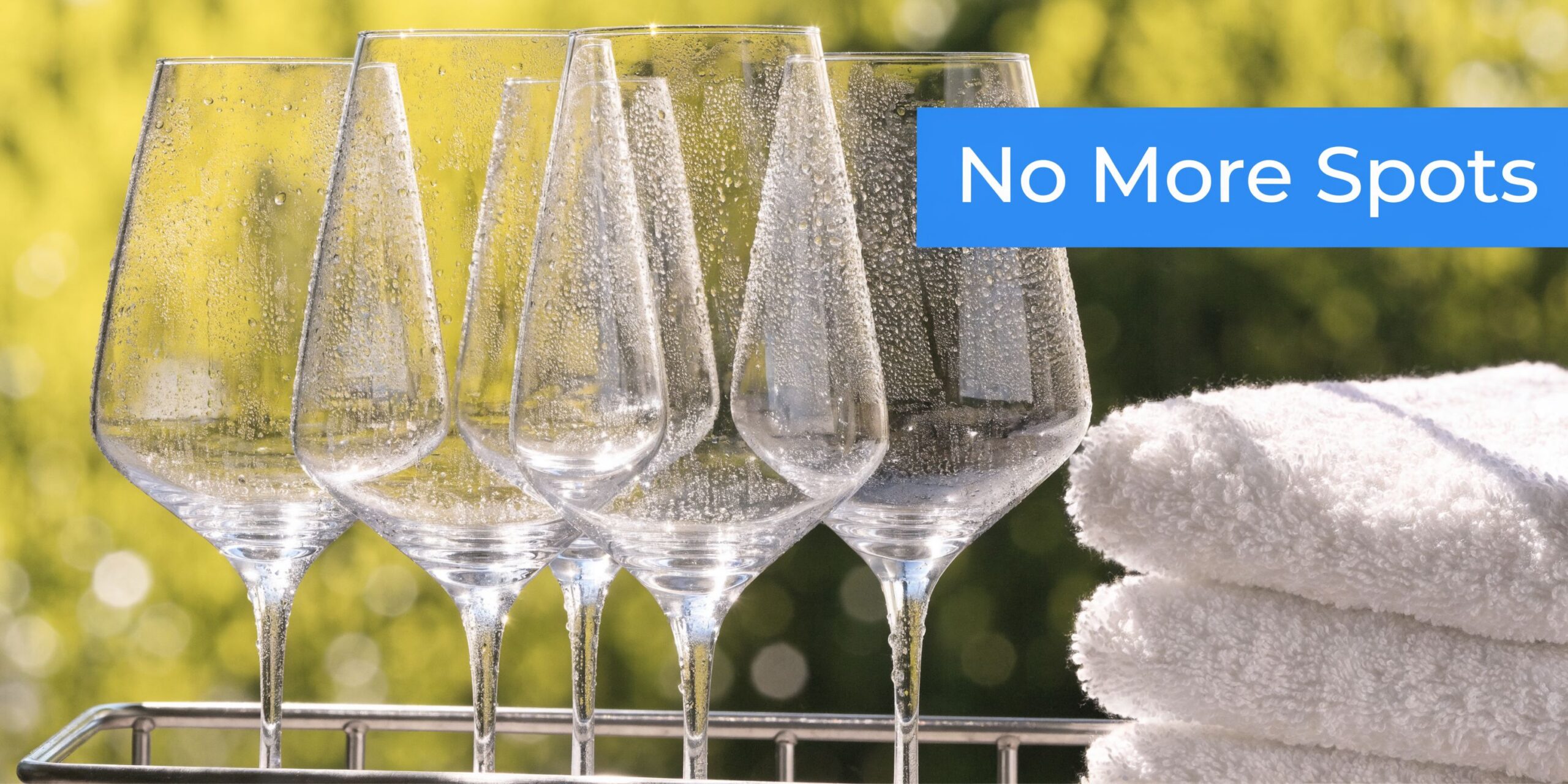 Several clean wine glasses sitting on a drying rack next to a stack of soft white towels.